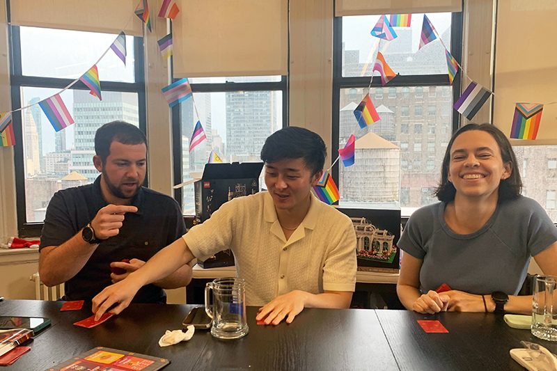 Three colleagues seated at a table playing a card game